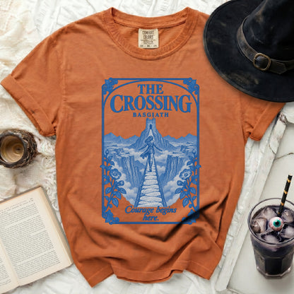 Orange t-shirt with blue graphic design featuring "THE CROSSING BASGIATH" and "Courage begins here."