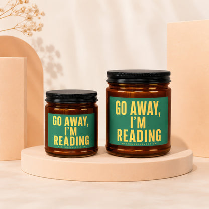 Two amber glass candles with green labels that read "GO AWAY, I'M READING."