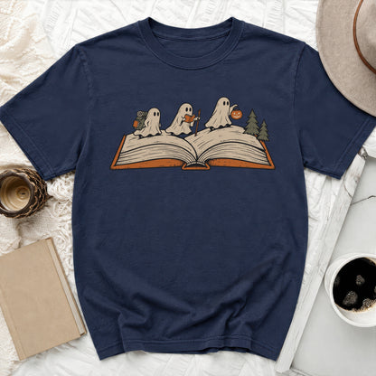 Three ghosts read from an open book with a pumpkin and trees.