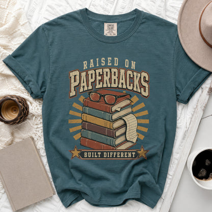 Teal t-shirt with "Raised on Paperbacks Built Different" text and book graphic.