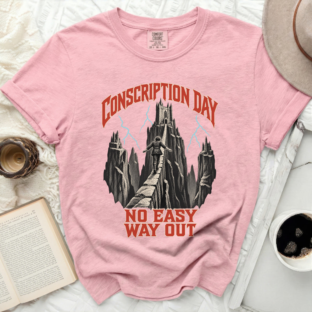 Pink t-shirt with a graphic of a person walking a narrow bridge toward a castle, surrounded by text reading CONSCRIPTION DAY NO EASY WAY OUT.