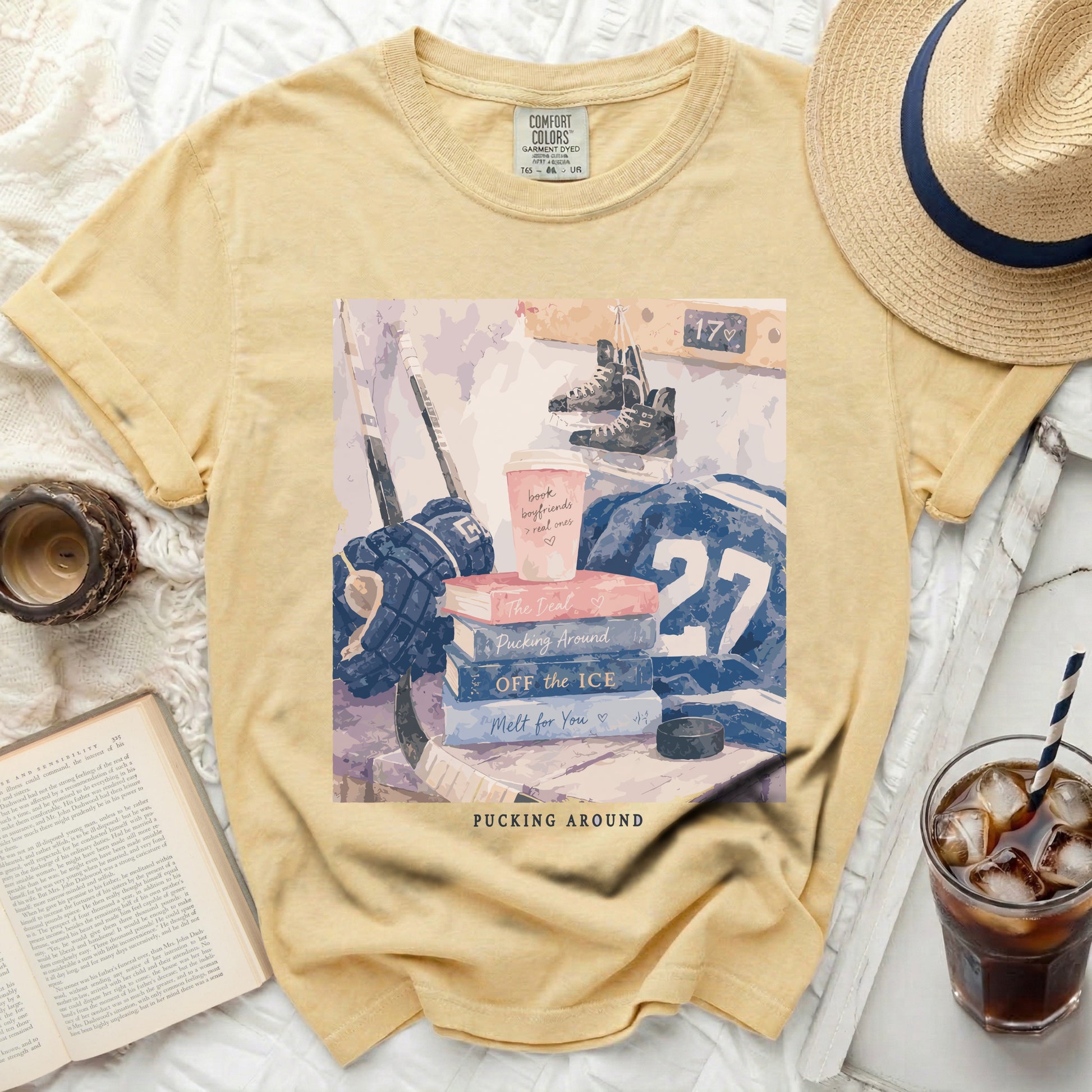 Yellow t-shirt with stacked books and hockey gear, reading "Pucking Around".