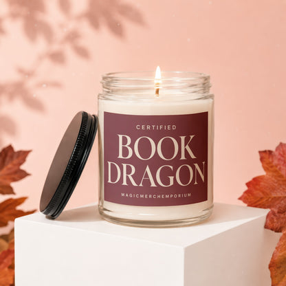 Glass candle labeled "Certified Book Dragon" with lid off and flame lit.