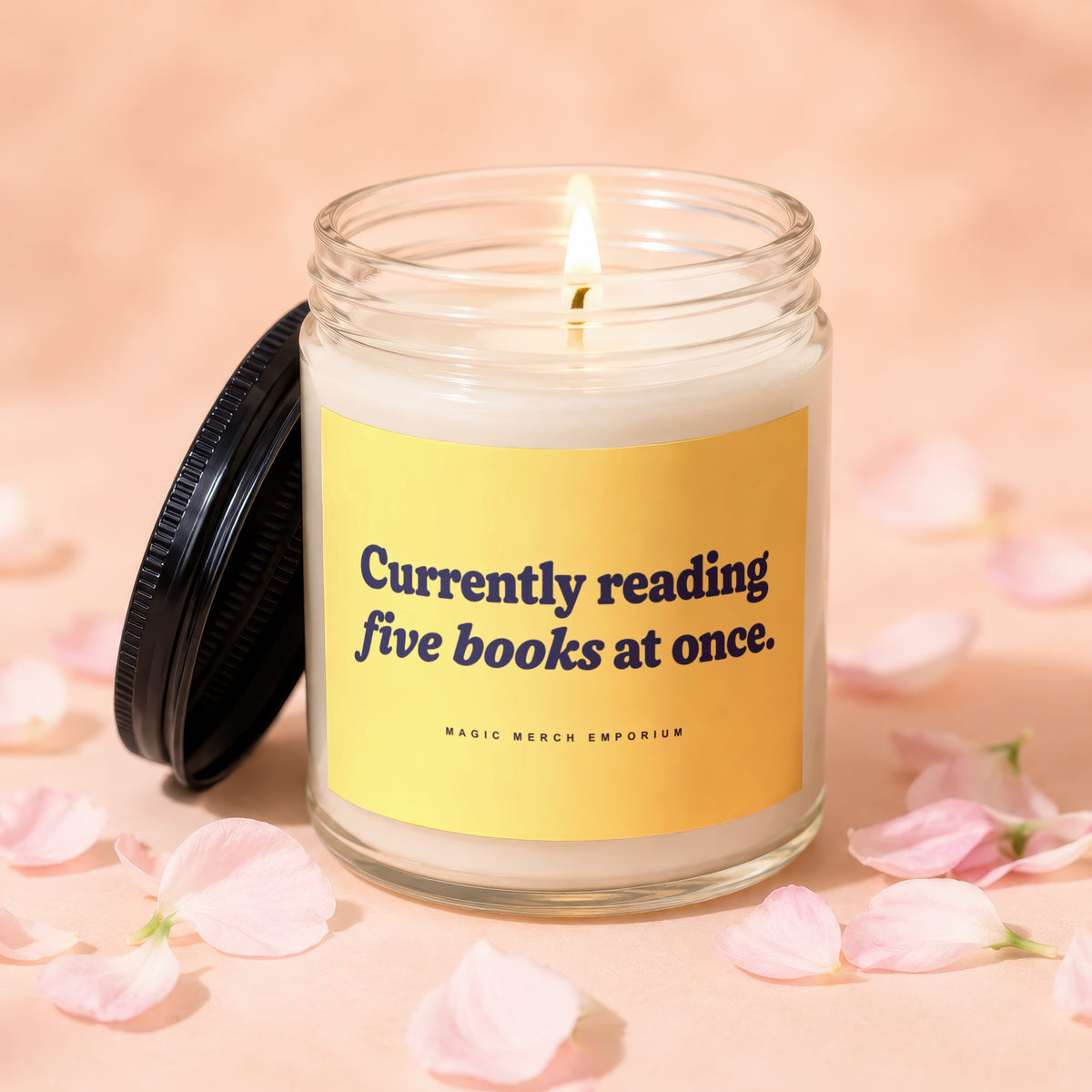 A lit candle in a clear glass jar with a black lid and yellow label.