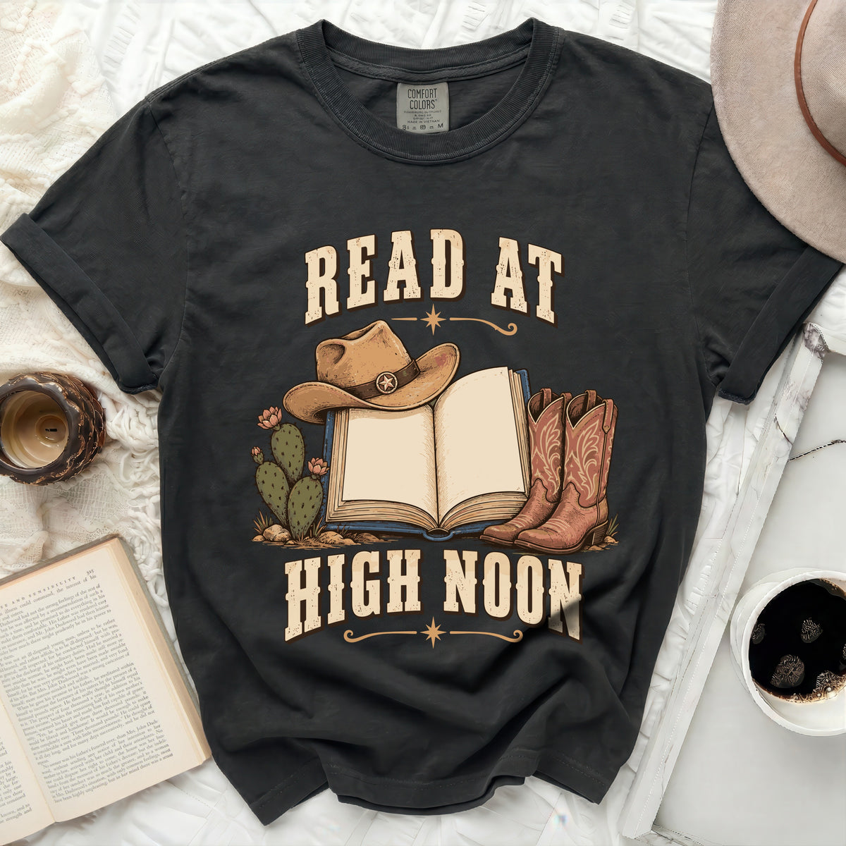 Graphic t-shirt with cowboy hat, book, boots, and "READ AT HIGH NOON" text.
