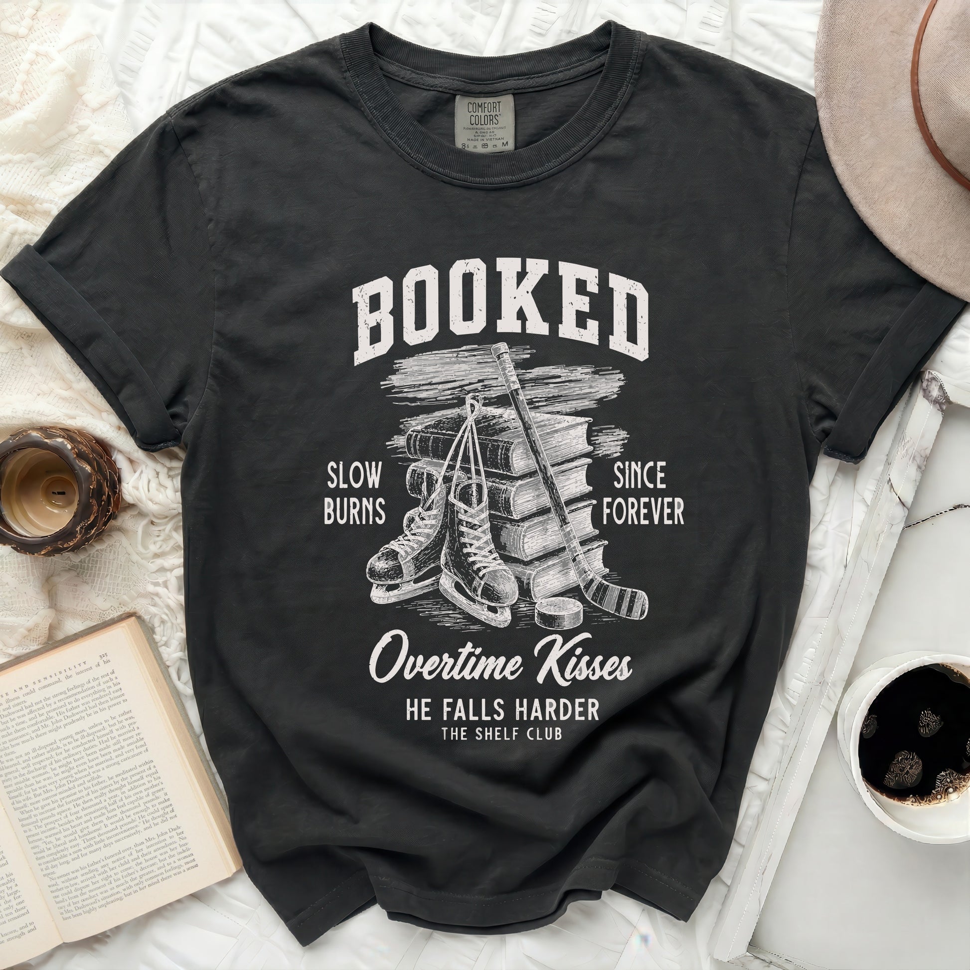 Black Comfort Colors t-shirt with "BOOKED" and book/ice skate graphic.