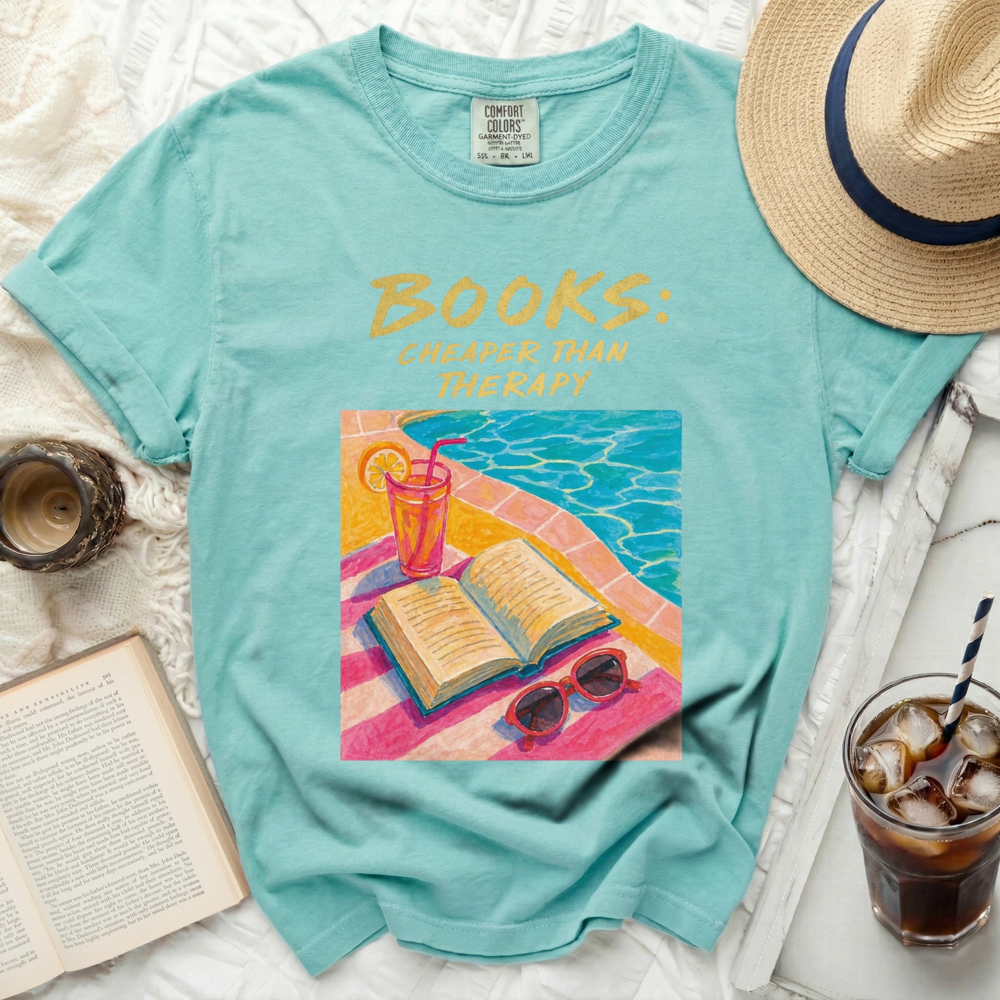 Aquamarine t-shirt with "Books: Cheaper Than Therapy" text and poolside illustration.