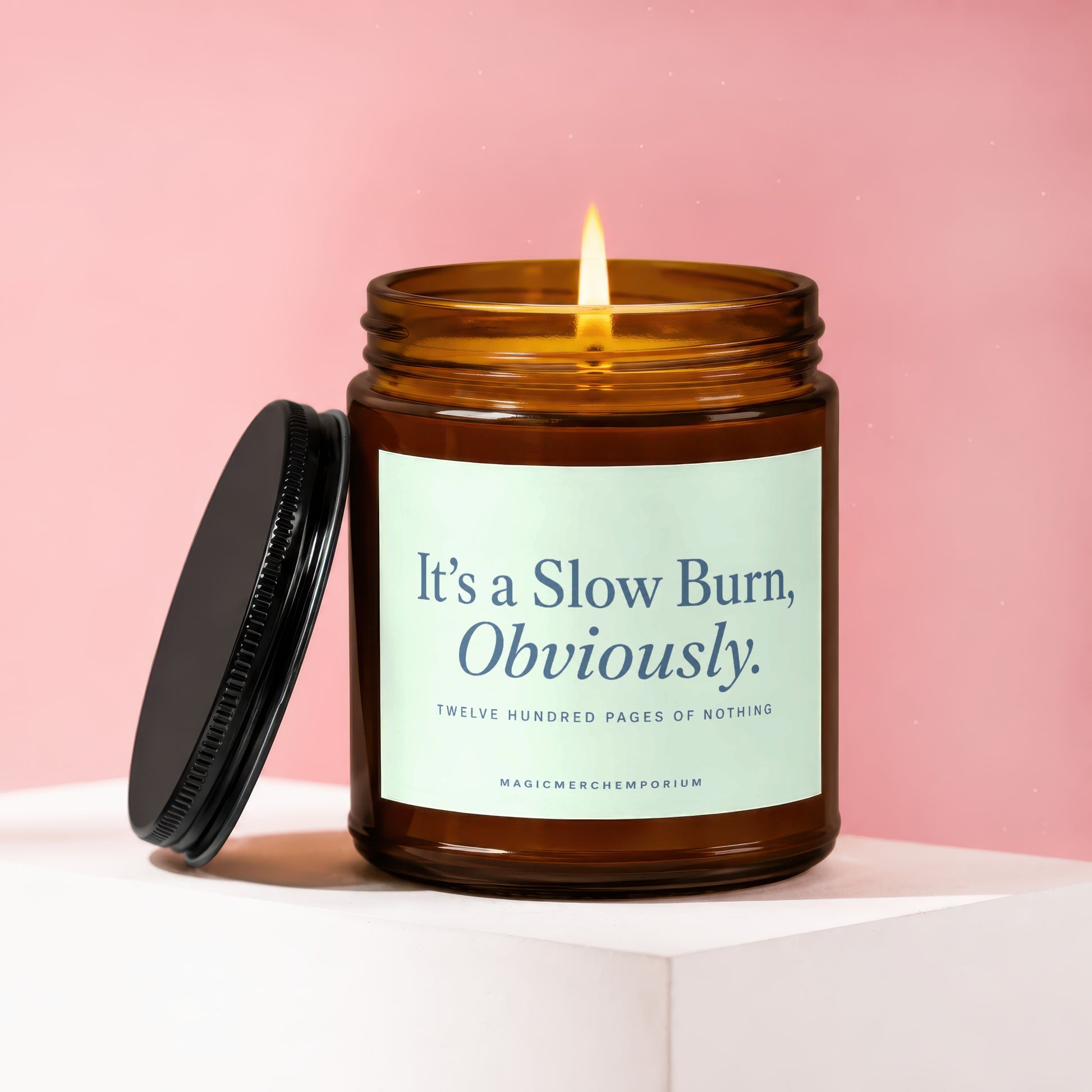 Lit amber candle with "It's a Slow Burn, Obviously." text on a pale blue label.