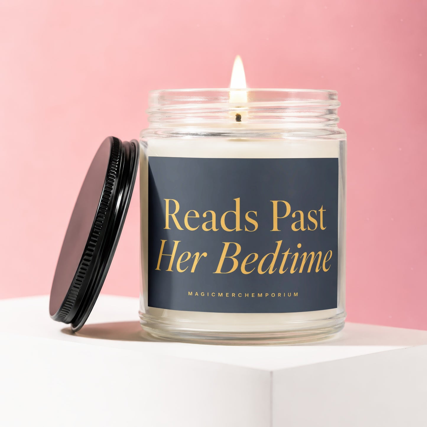 Glass candle with lit wick, black lid, and text "Reads Past Her Bedtime".