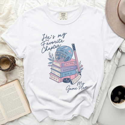 White t-shirt with "He's my favorite chapter" and hockey graphics.