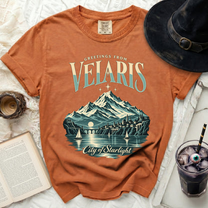 Orange t-shirt with "Greetings from Velaris City of Starlight" graphic.