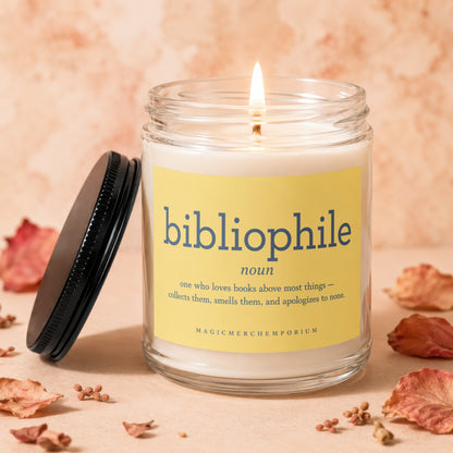 A lit candle in a jar with a yellow label that says "bibliophile noun [...] MAGICMERCHEMPORIUM"