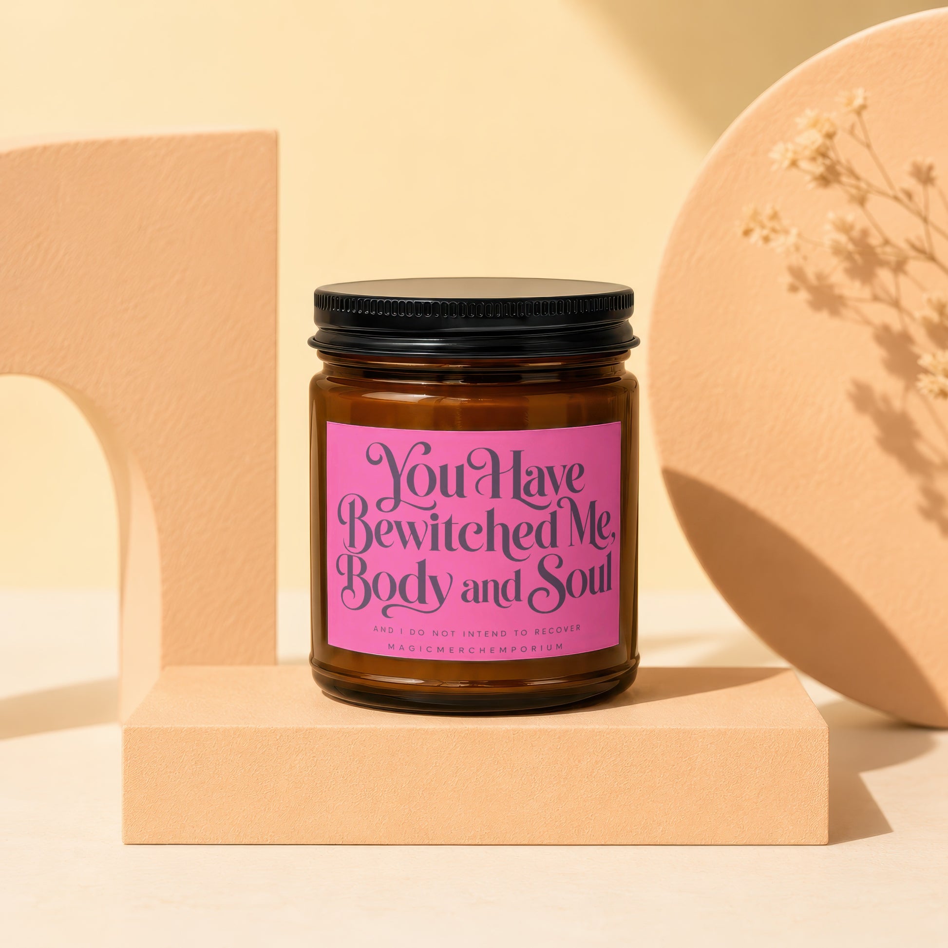 Amber glass candle with pink label reading "You Have Bewitched Me, Body and Soul."