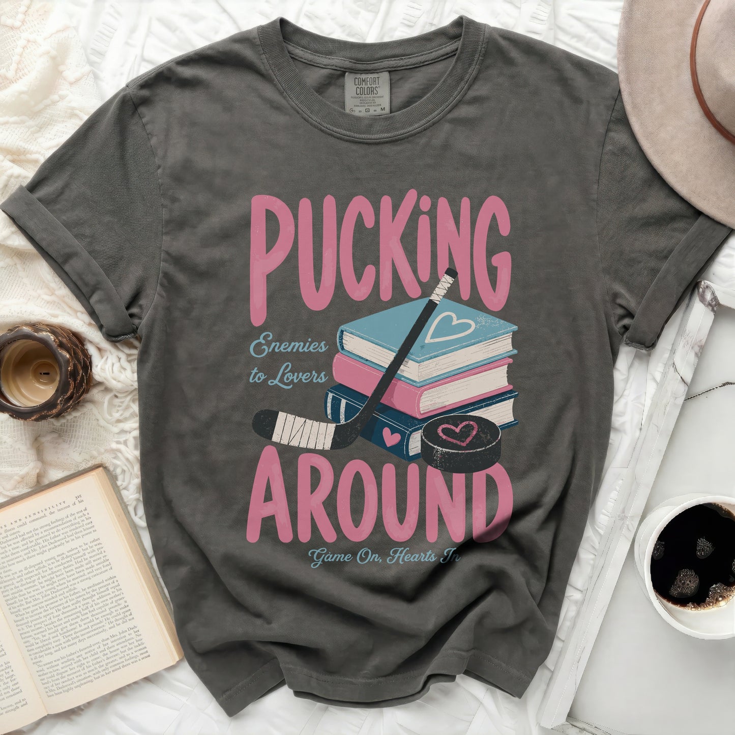 Grey t-shirt with pink text "Pucking Around" and "Enemies to Lovers" over books.