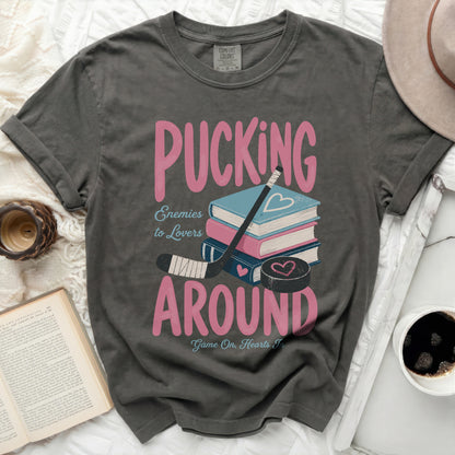Grey t-shirt with pink text "Pucking Around" and "Enemies to Lovers" over books.