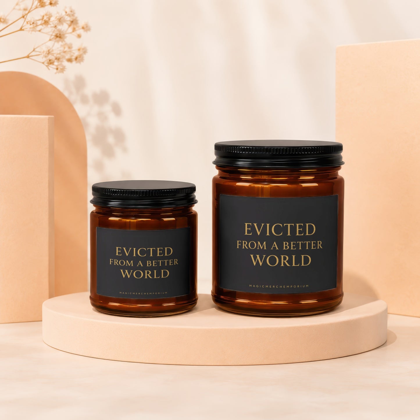 Two amber glass candles with black lids and labels reading "Evicted from a Better World."