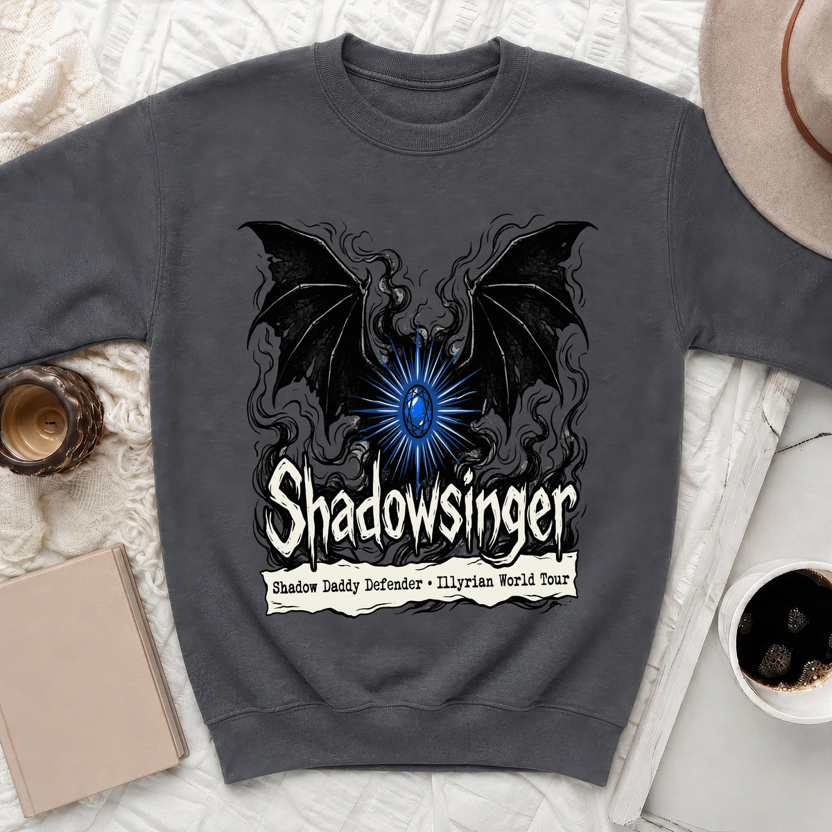 Charcoal grey crewneck sweatshirt featuring a graphic with black bat wings, a glowing blue gem, and text reading "Shadowsinger Shadow Daddy Defender Illyrian World Tour".