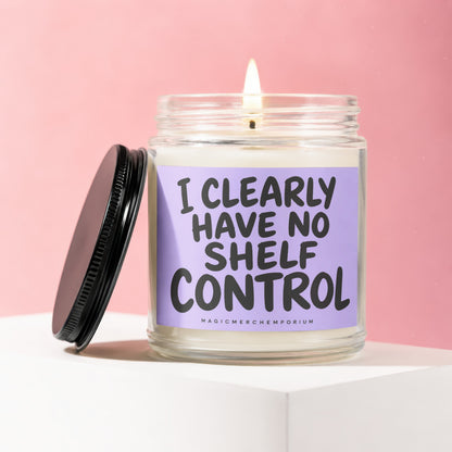Lit candle in glass jar with black lid and purple label that reads "I CLEARLY HAVE NO SHELF CONTROL."