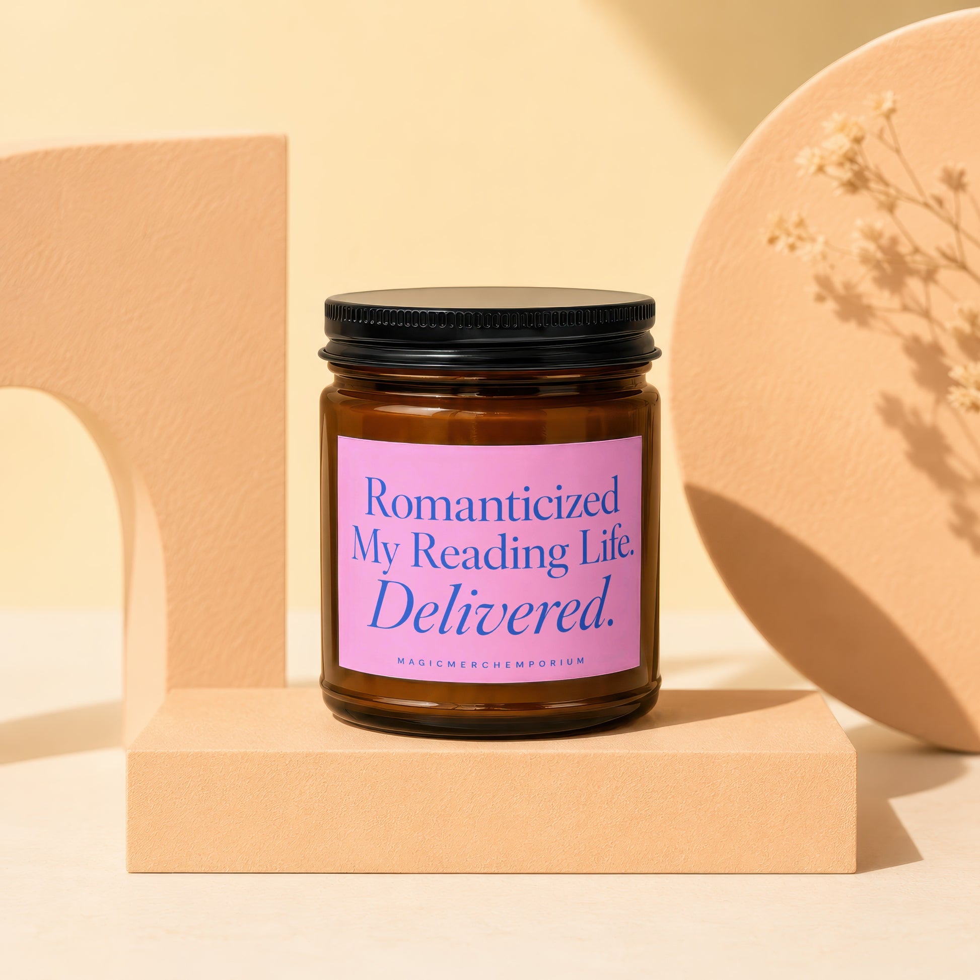 Amber jar candle with a pink label reading "Romanticized My Reading Life. Delivered."