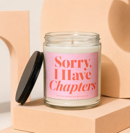 Glass candle with pink label reading "Sorry, I Have Chapters"