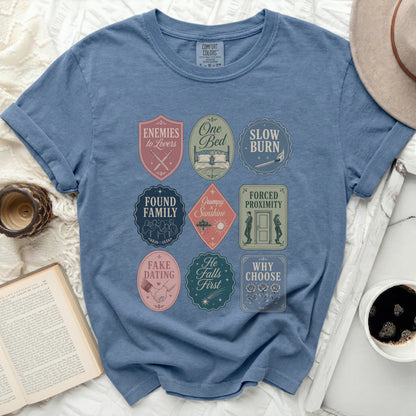 Blue t-shirt with nine romance novel trope badges.