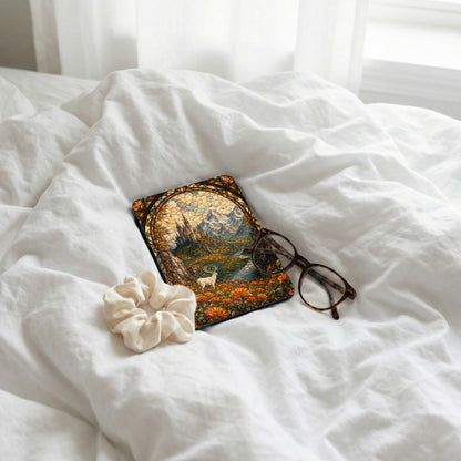 Case with stained glass art, including a deer, castle, and mountains, placed on crumpled white sheets.