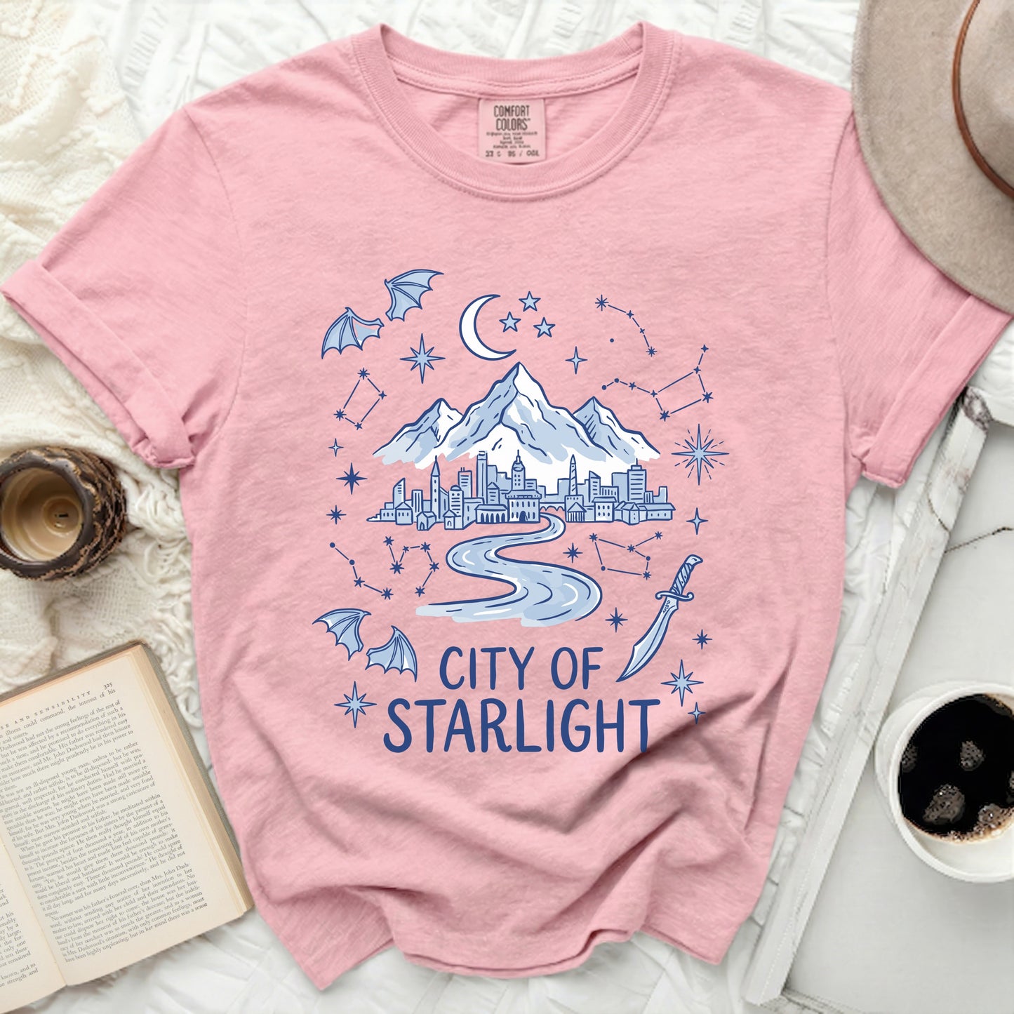 Pink t-shirt with "City of Starlight" graphic featuring city, mountains, moon, bats, sword, and constellations.
