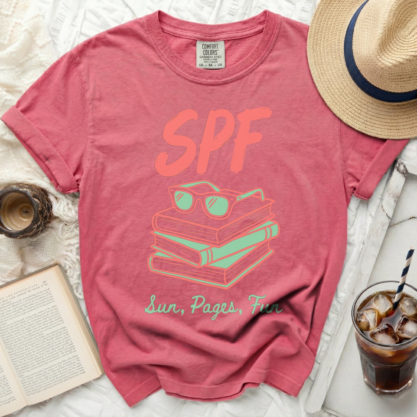 T-shirt with stacked books, sunglasses, and text "SPF Sun, Pages, Fun".