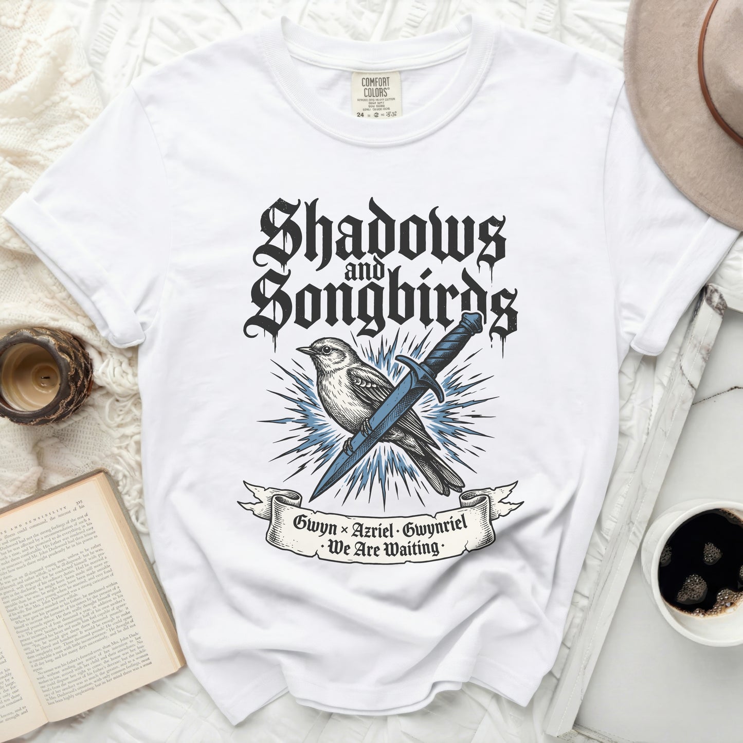 White t-shirt with "Shadows & Songbirds" text and bird illustration.