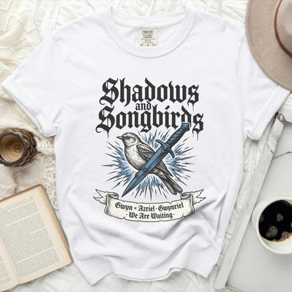 White t-shirt with "Shadows & Songbirds" text and bird illustration.
