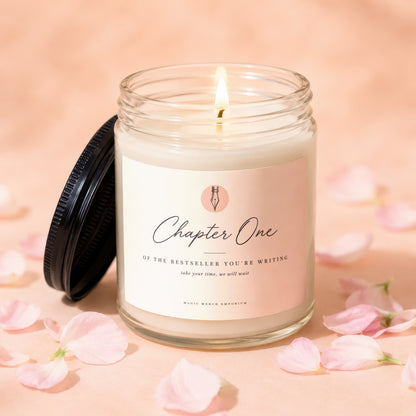 Lit candle in glass jar with "Chapter One" label, surrounded by pink petals.