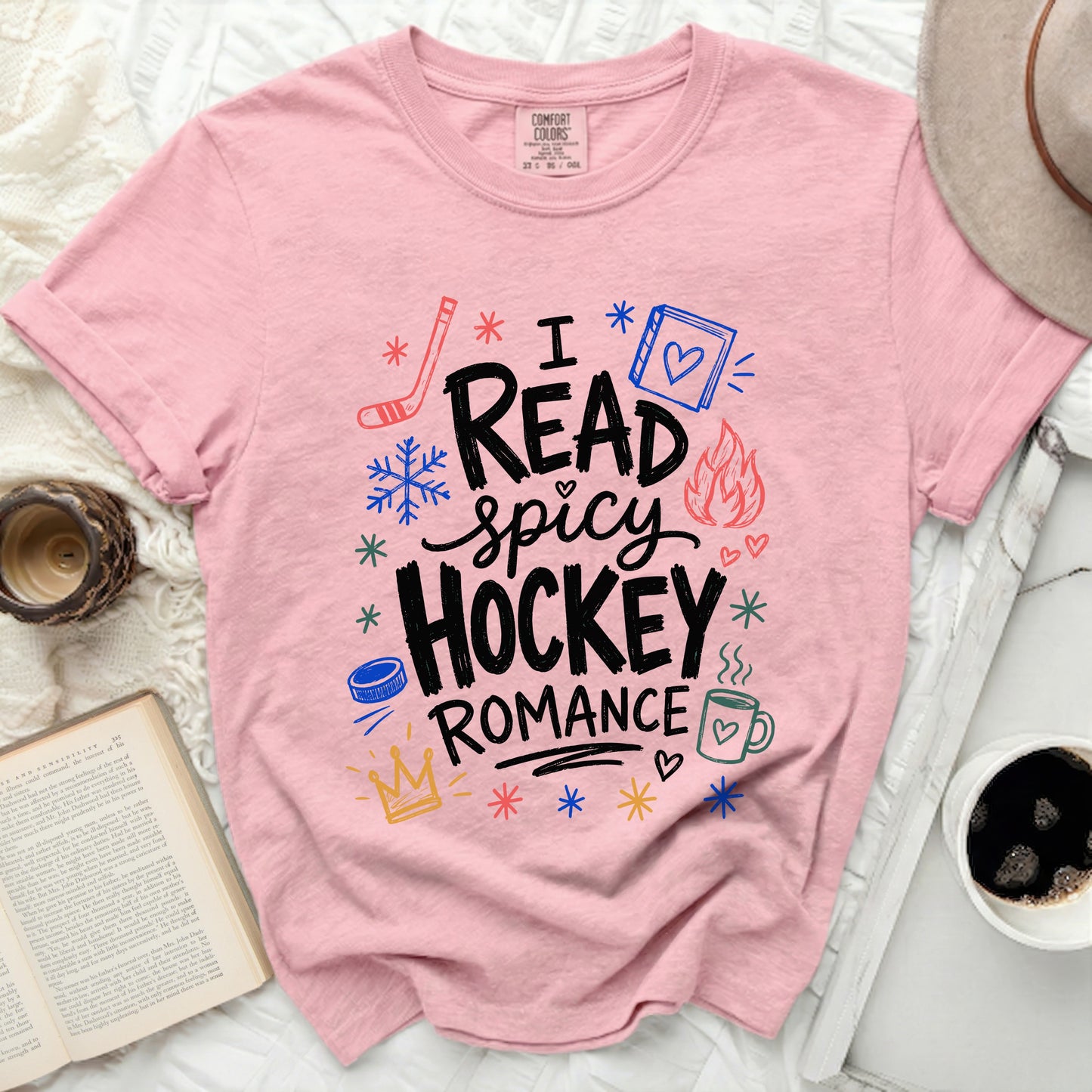 Pink t-shirt with "I read spicy hockey romance" and winter icons.