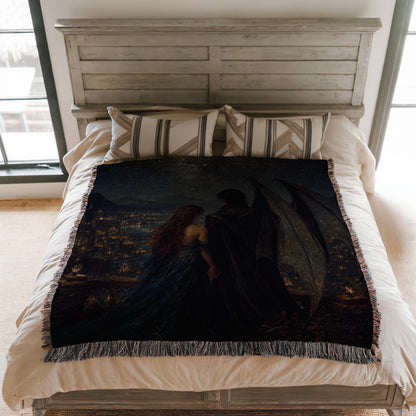 a bedroom with a bed featuring a large, dark-colored blanket with a painting of a woman and a man on it. The bed is set against a white wooden headboard, and there are pillows on the bed.
