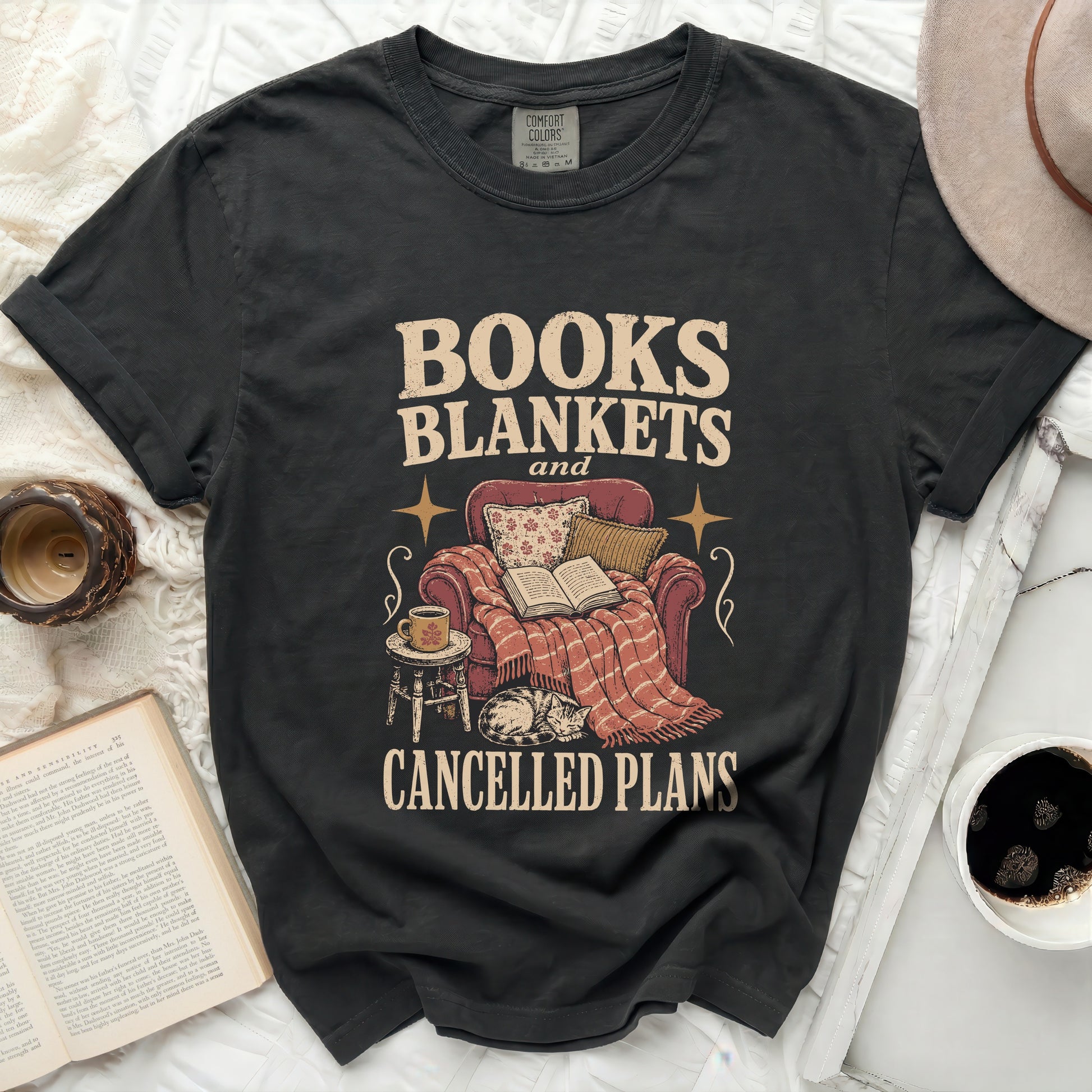 Dark t-shirt with "BOOKS BLANKETS and CANCELLED PLANS" graphic.