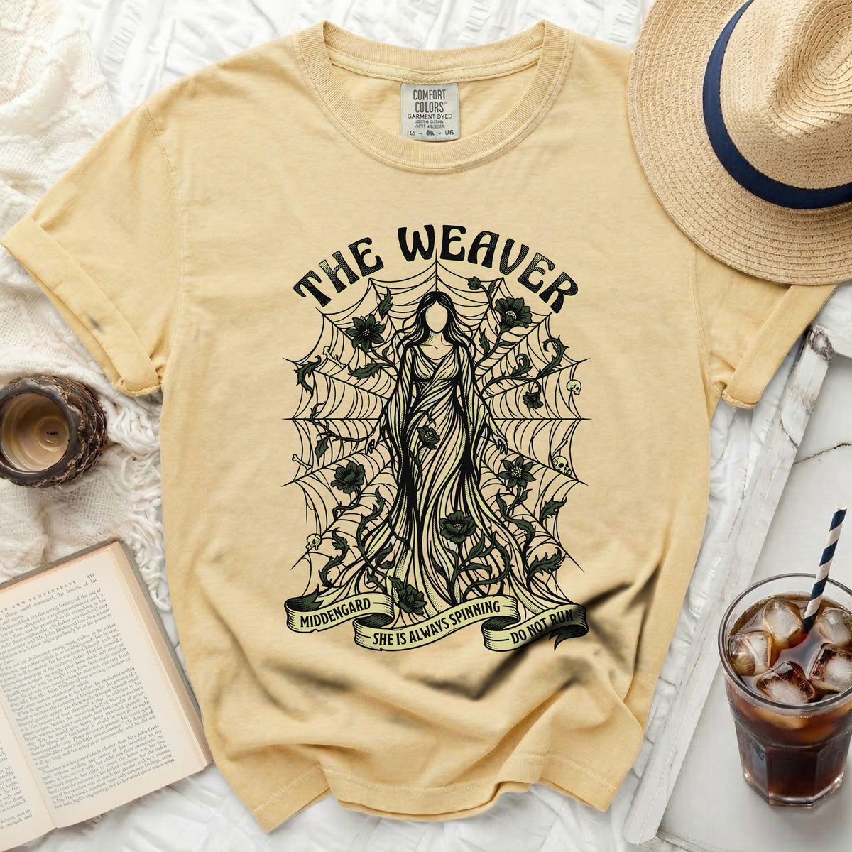 Yellow t-shirt with The Weaver graphic, spiderwebs, and quote "SHE IS ALWAYS SPINNING DO NOT RUN".