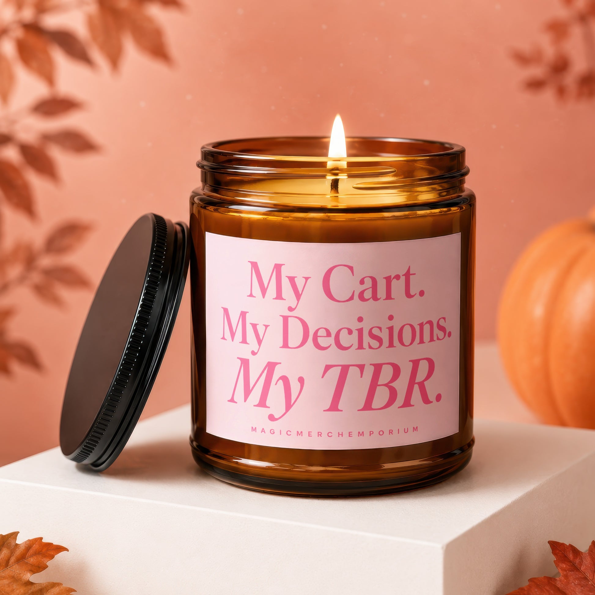 Amber jar candle with lit wick, pink label text "My Cart. My Decisions. My TBR. MAGICMERCH_EMPORIUM."