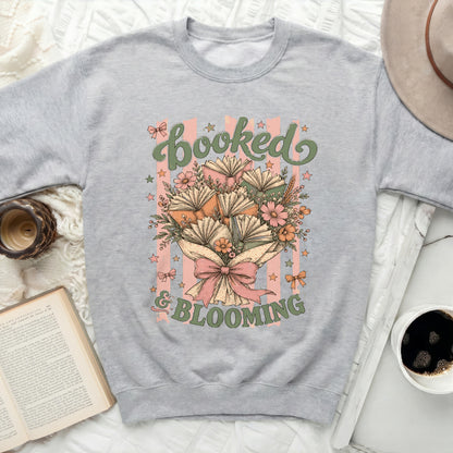 Sweatshirt with "Booked & Blooming" text and floral book graphic.