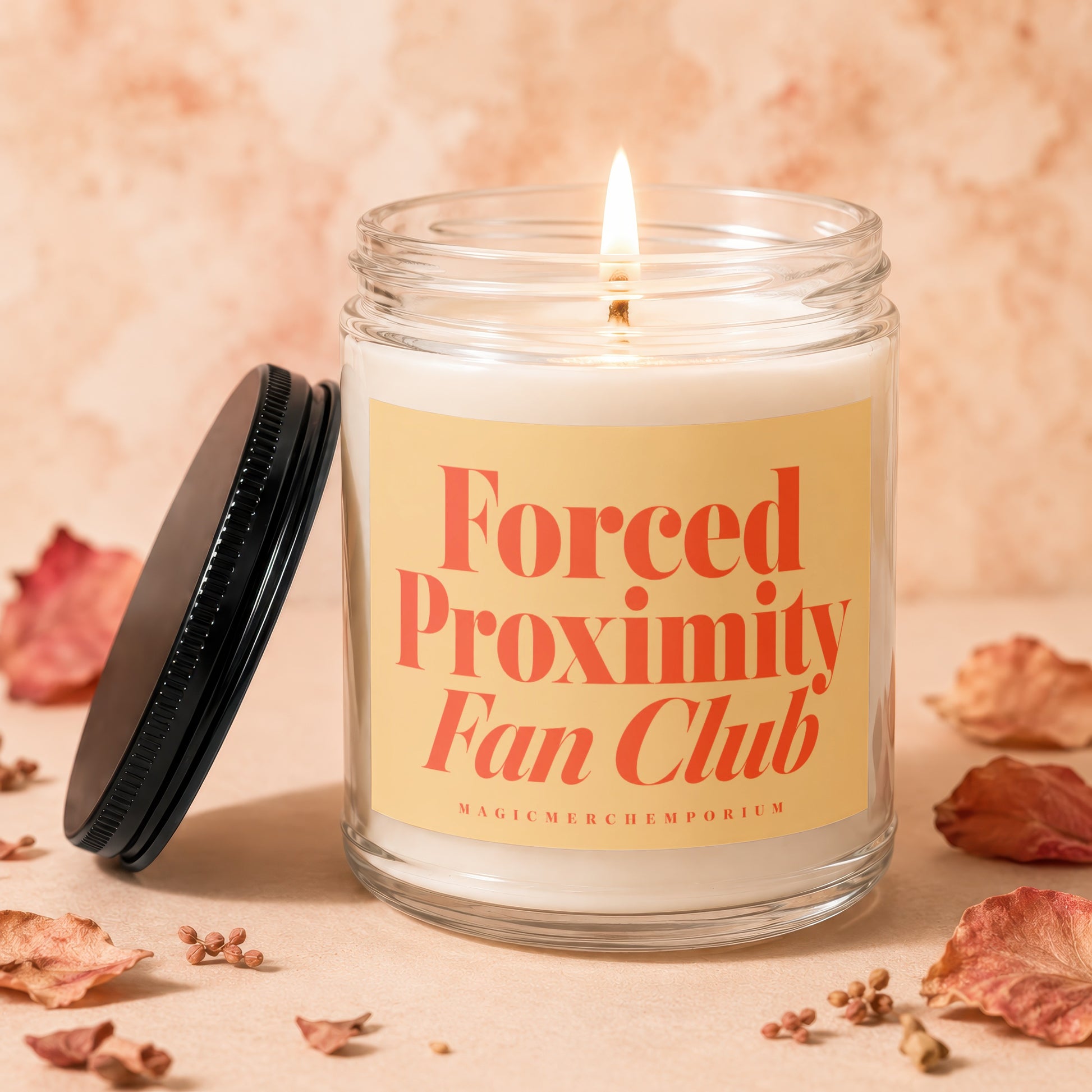 Lit candle in glass jar with cream wax, cream label reads "Forced Proximity Fan Club".