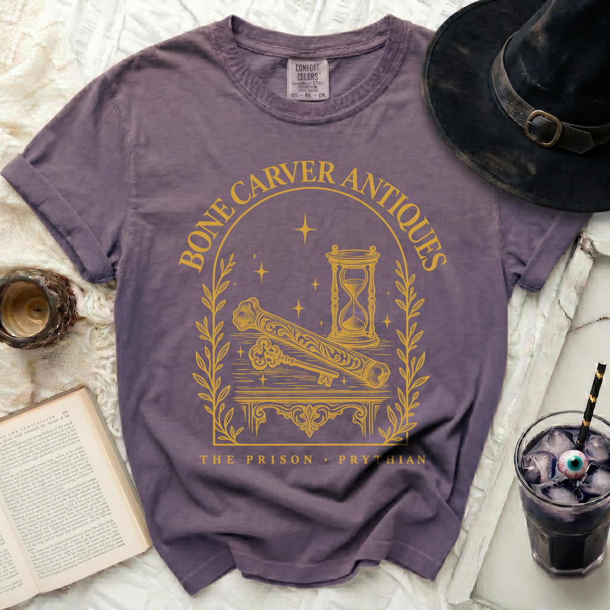 Vintage wash purple t-shirt featuring a gold graphic of an hourglass, bone, and key.