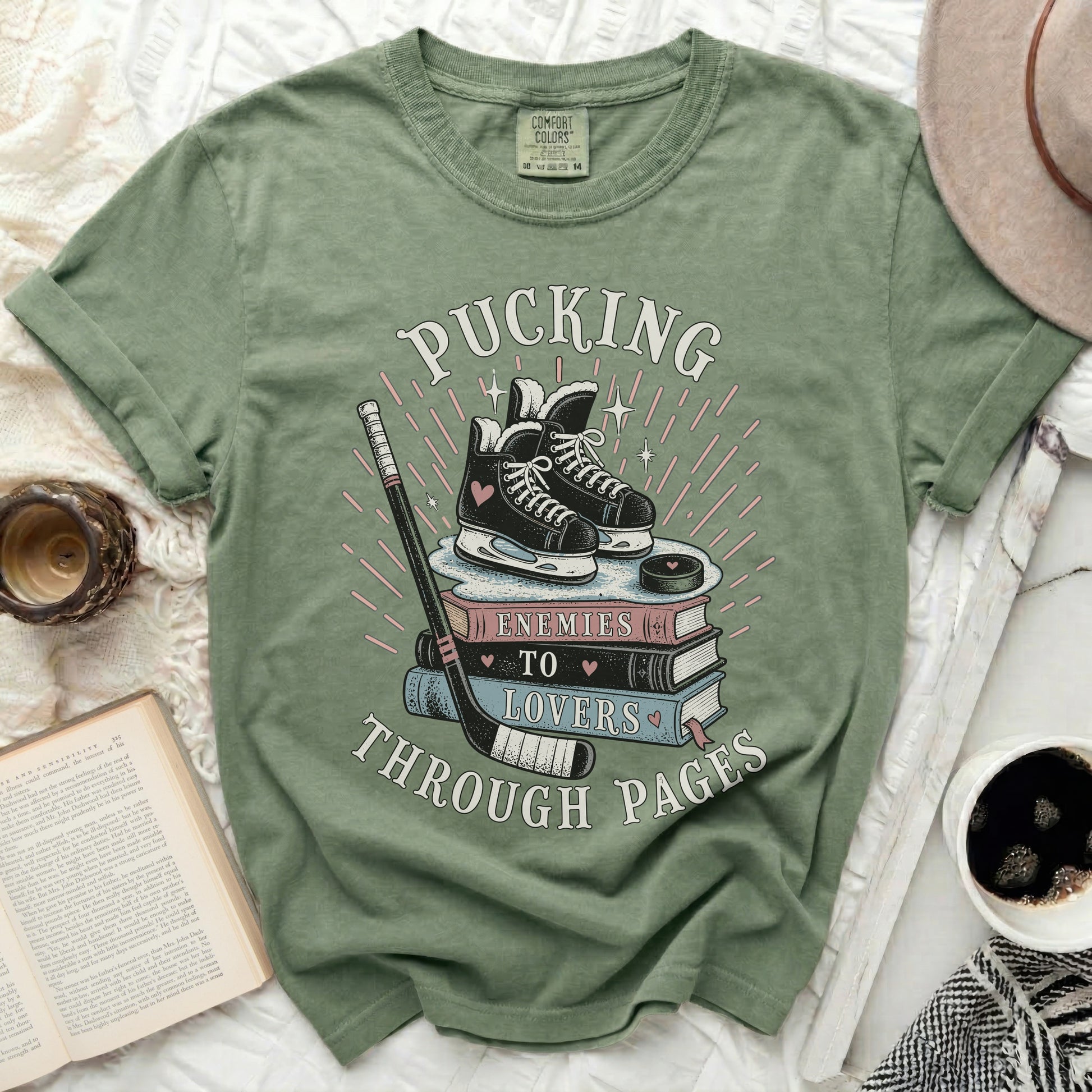 Green t-shirt with stacked books, ice skates, and hockey stick graphic.