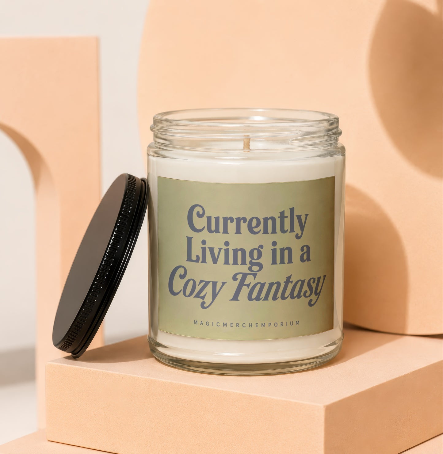 Candle with black lid, label reads "Currently Living in a Cozy Fantasy".