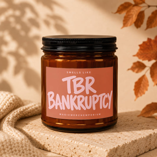 Amber jar candle with a pink label reading "Smells Like TBR Bankruptcy MagicMerchEmporium".