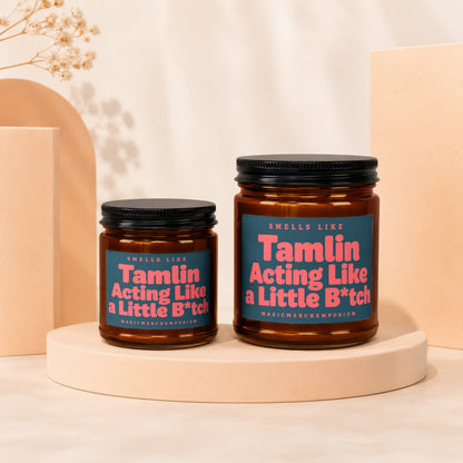 Two amber glass candles with black lids, labeled "Tamlin Acting Like a Little B*tch".