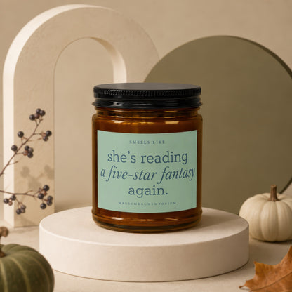 Amber jar candle with label reading "she's reading a five-star fantasy again."