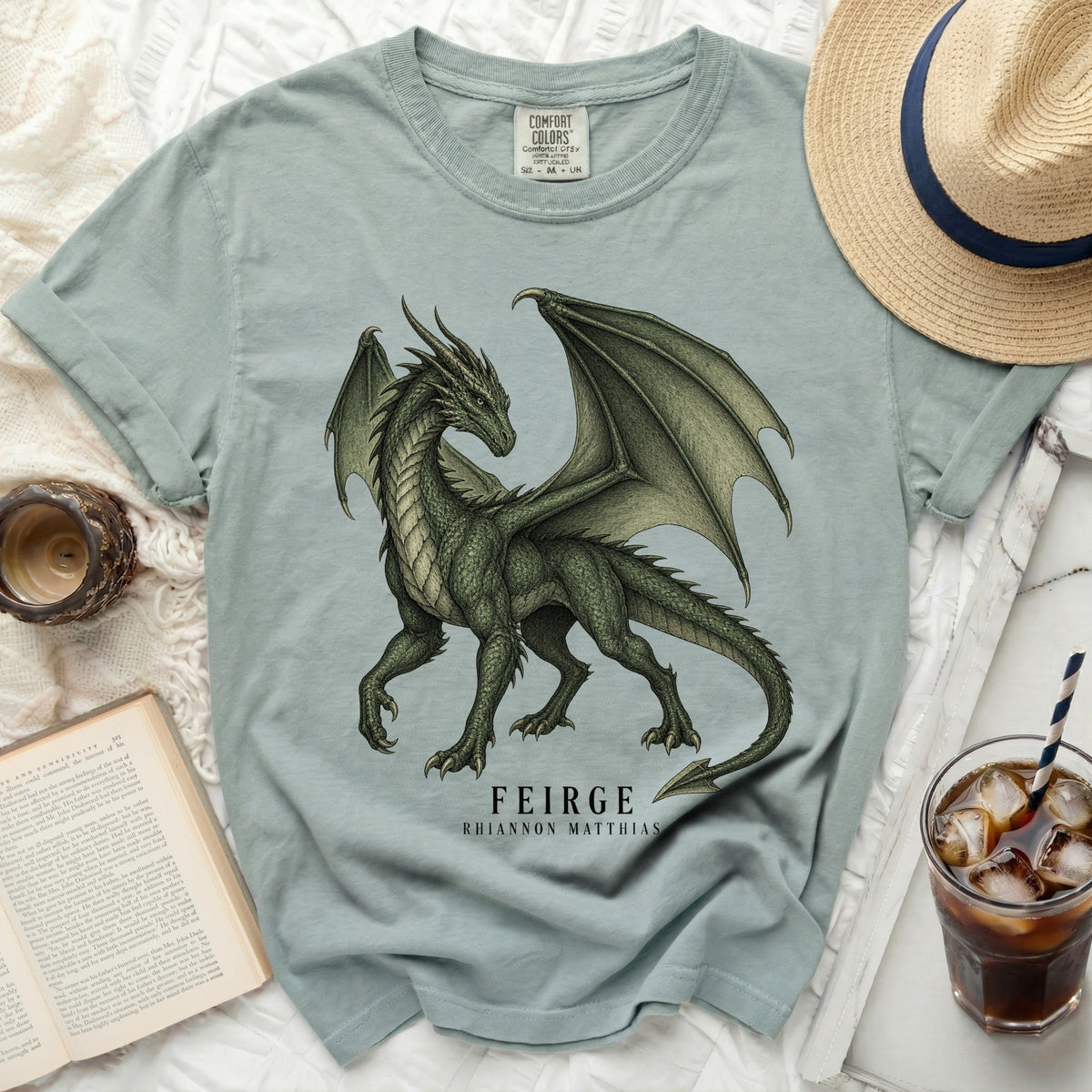 Light blue t-shirt with a green dragon graphic and text "FEIRGE RHIANNON MATTHIAS".