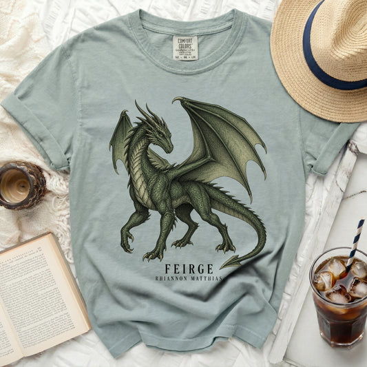 Light blue t-shirt with a green dragon graphic and text "FEIRGE RHIANNON MATTHIAS".