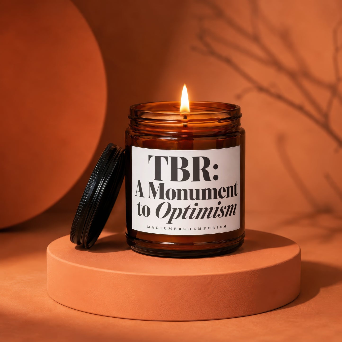 Lit glass candle with label "TBR: A Monument to Optimism".