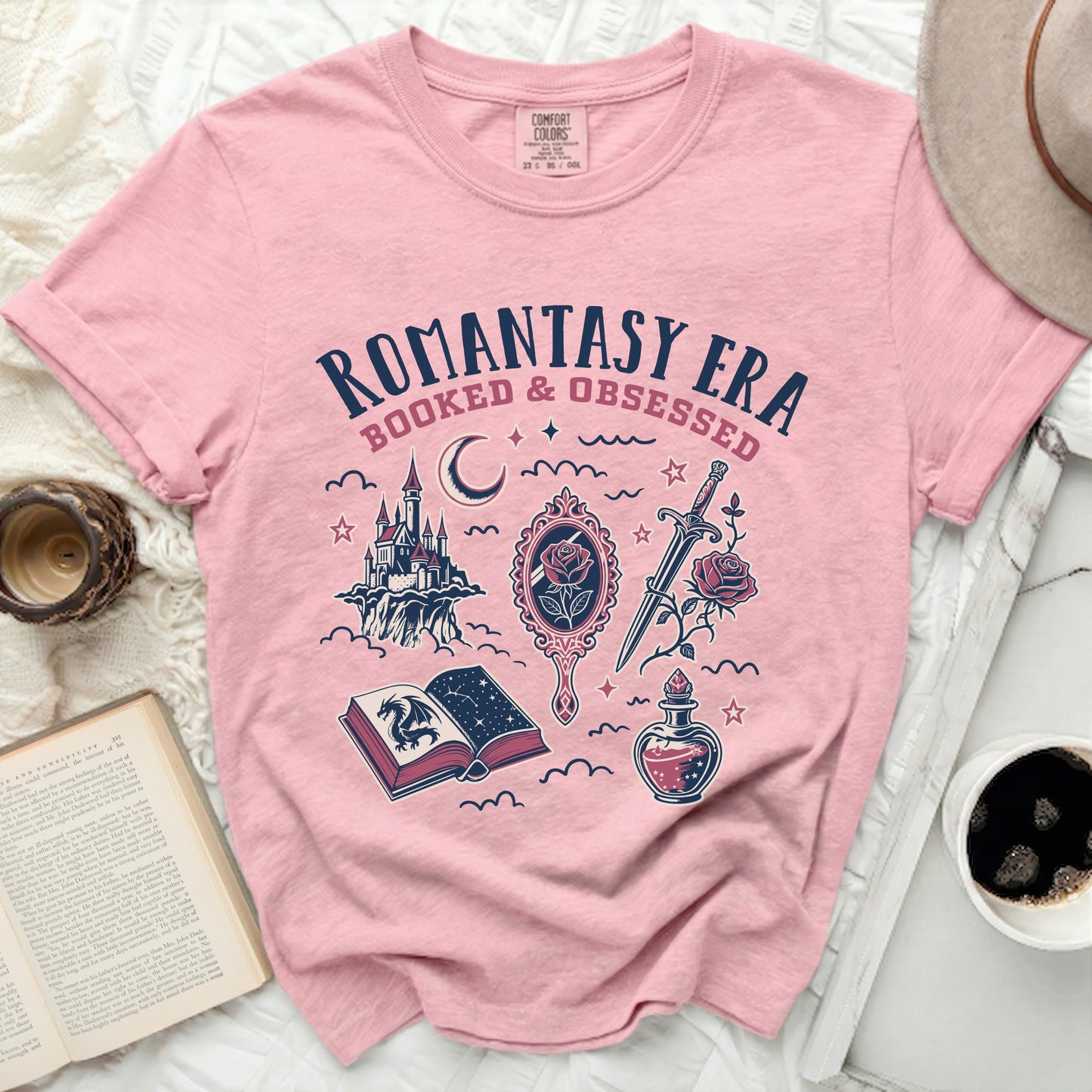 Pink t-shirt with "Romantasy Era Booked & Obsessed" text over fantasy illustrations.