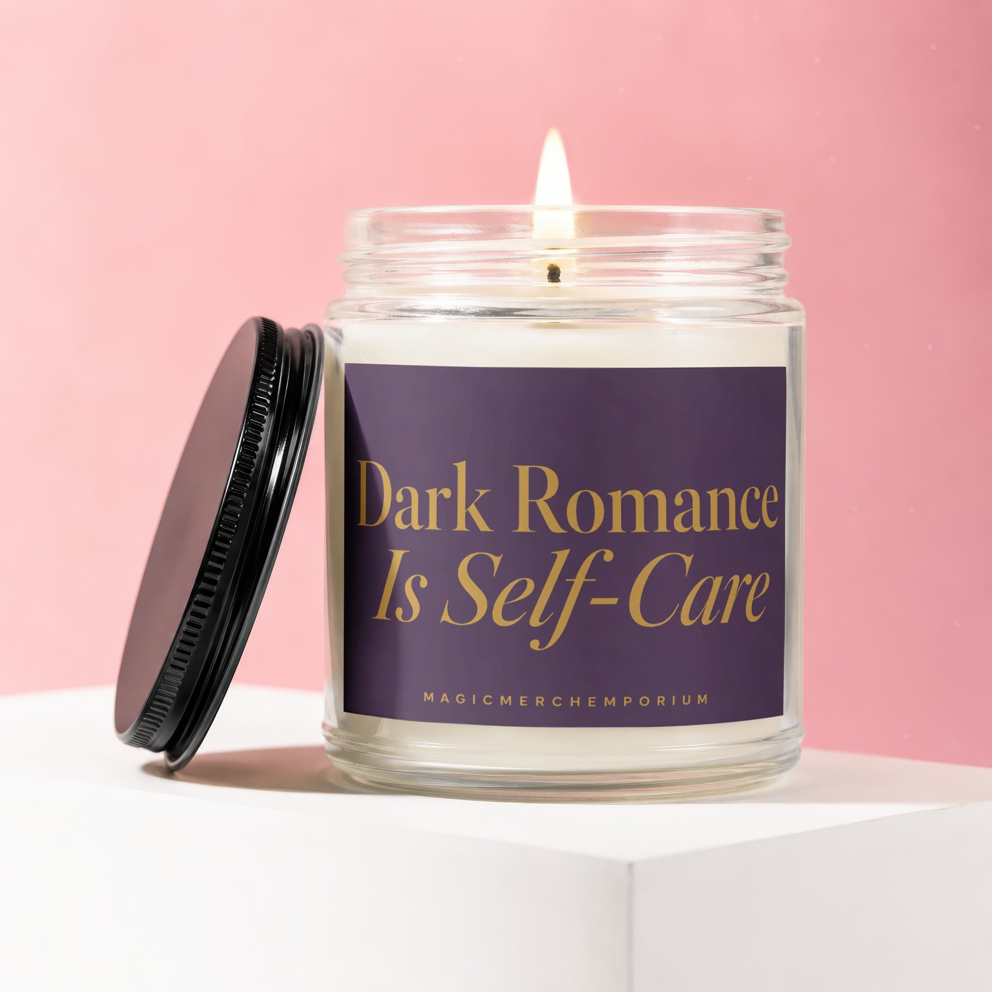 Lit candle in glass jar with dark purple label that reads "Dark Romance Is Self-Care"
