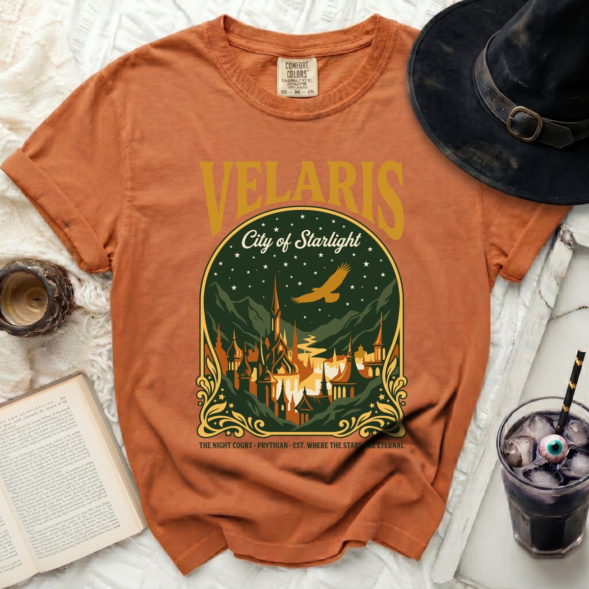 Orange t-shirt with "Velaris City of Starlight" graphic and witch hat.